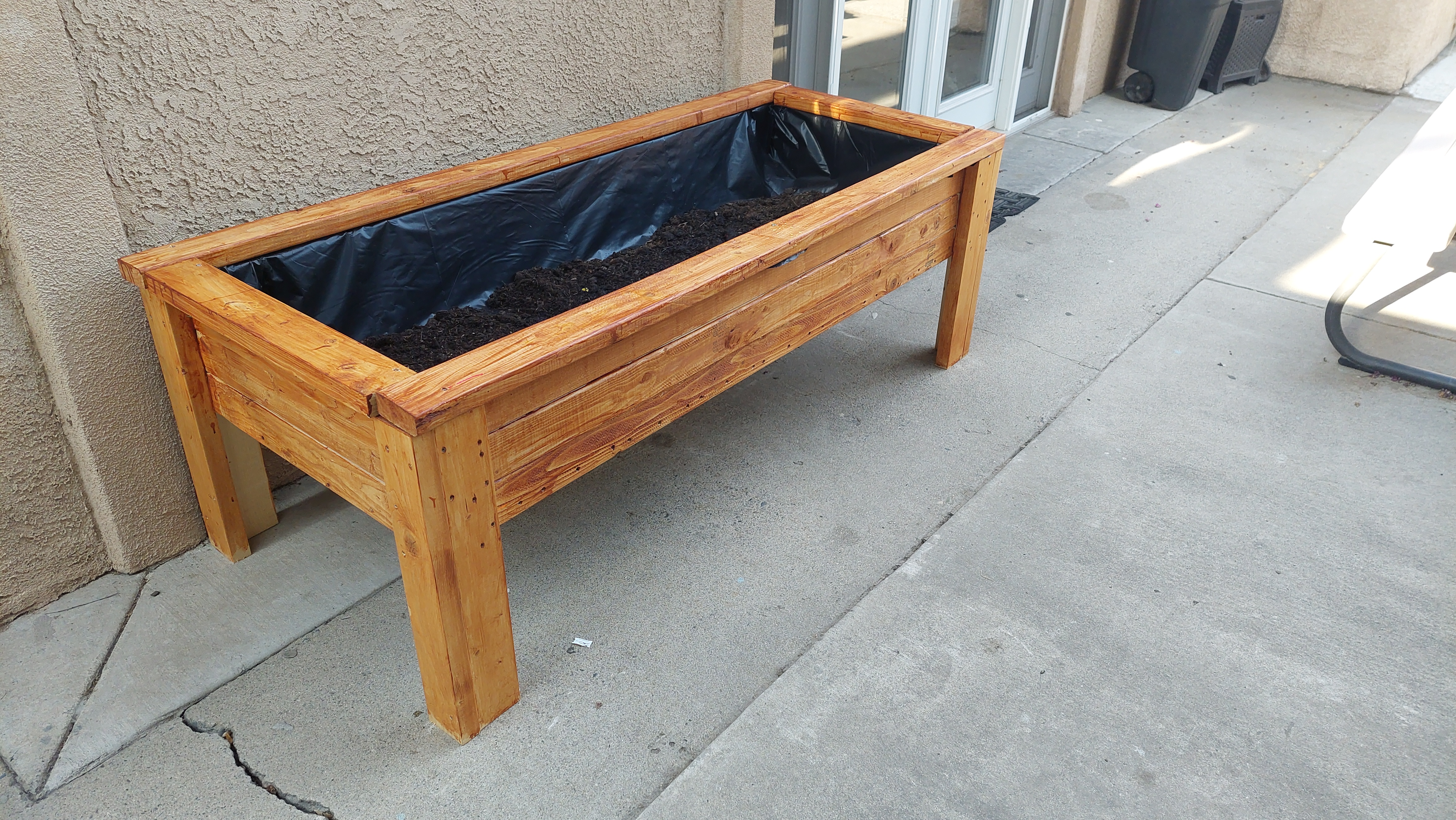 Planter box now complete with dirt-filled plastic lining and stain